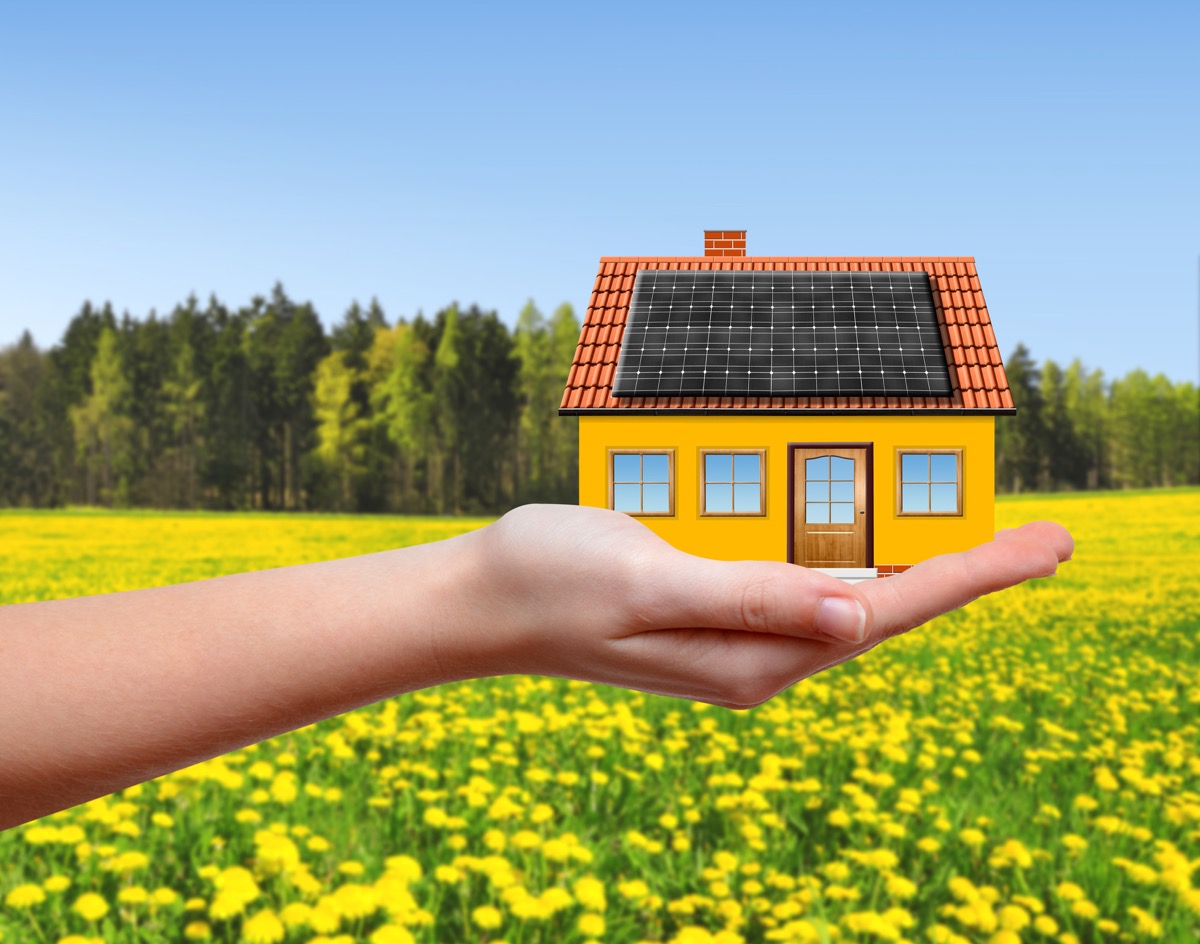 A model solar-powered home resting in a person’s hand